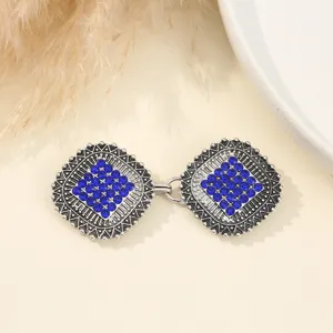 Vista dettagliata di chiusure per mantello in metallo strass, eleganti bottoni blu.