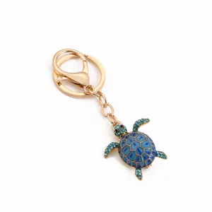 Detailed view of a cute blue rhinestone turtle pendant keychain with gold alloy rings and clasp.