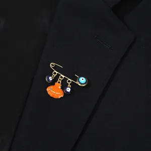 Broche épingle de sûreté mauvais œil avec breloques yeux bleus et pendentif coquillage orange.