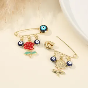 Gold tone safety pin brooch with blue evil eye beads and red rose charm for stylish accessory.