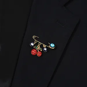 Vue détail broche cerise œil maléfique, épingle de sûreté dorée aux cristaux rouges.