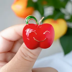 Cute red apple brooch pin with smiling face design, enamel fashion accessory for women clothes.