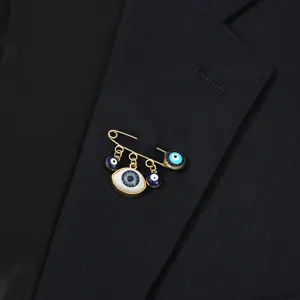 Evil eye safety pin brooch featuring blue enamel eye charms, gold tone metal collar pin detail.