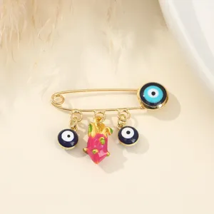 Broche épingle de sûreté dorée ornée de perles mauvais œil et d'un pendentif fruit du dragon.