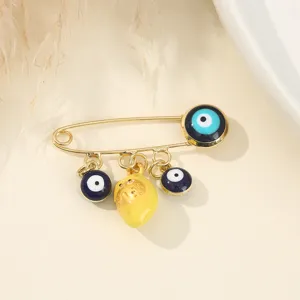 Vue détaillée de la broche mauvais œil avec perles en émail bleu et pendentif jaune pour style unique.