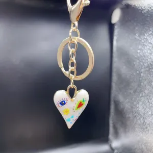 Alloy heart keychain with colorful enamel eye and flower design for bags and cars.