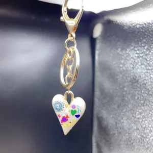 Detailed view of alloy heart keychain with cute eye and star charms, gold bag pendant.