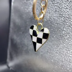 Close-up detail of a chic black and white checkered heart pendant keychain and bag charm.