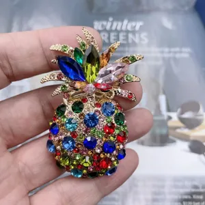 Close-up of colorful rhinestone pineapple brooch, sparkling crystal details and gold-tone finish.