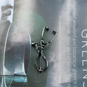 Stethoscope brooch detail view, creative medical series accessory, black metal finish.