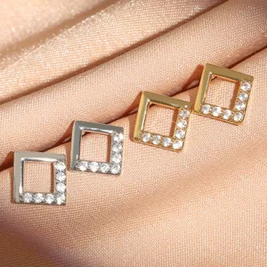 Primo piano di orecchini geometrici quadrati con zirconi pavé, oro e argento dettagli.