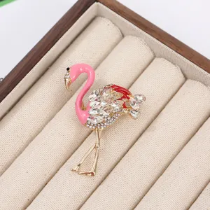Detail shot of sparkling rhinestone flamingo brooch with pink enamel and gold tone metal finish.