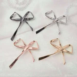 Spilla a forma di fiocco in metallo vista dettaglio, elegante accessorio moda, finitura in 4 colori.