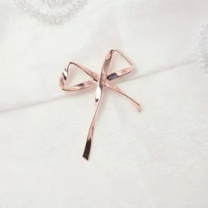 Primo piano di una spilla a fiocco in oro rosa, elegante accessorio di moda per abiti chic.