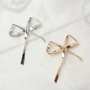 Primo piano di eleganti spille a fiocco argento e oro, accessorio moda in metallo chic.