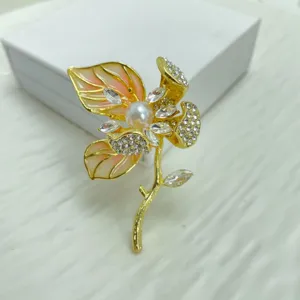 Detailed shot of an elegant gold-toned floral brooch featuring sparkling rhinestones and a pearl.