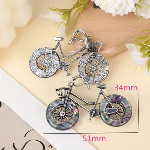Retro silver alloy bicycle brooch detail with unique shell wheels for clothing decor.