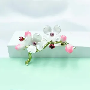 Detailed view of exquisite floral brooch with pink petals, green stem, and sparkling crystals.