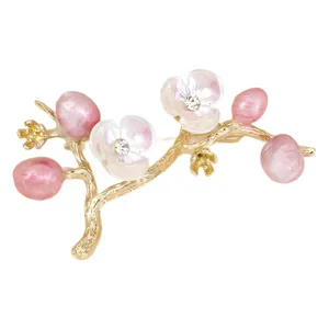 Elegant plum blossom brooch featuring shimmering crystals and pink pearls on a gold-toned branch.
