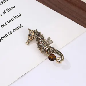 Close-up detail of vintage retro rhinestone seahorse brooch with amber crystal and antique bronze.