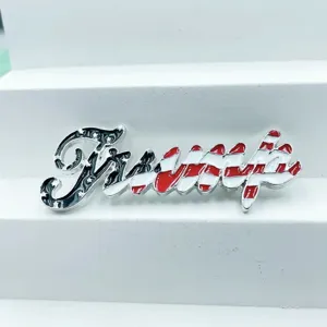 Vista detallada del broche de metal con letra Trump estilo bandera de EE. UU. y servilletero.