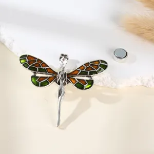 Close-up of the vintage dragonfly rhinestone brooch with green enamel wings and magnetic back.