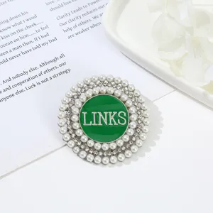 Round alloy brooch featuring layered pearls, rhinestones, and a green enamel LINKS center.