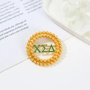 Close-up detail of a gold double-layer pearl round brooch pin with green Greek letters.
