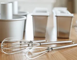 Detailed close-up shot of stainless steel mini spring whisk and baking molds for kitchen use.