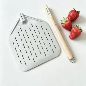 Perforated stainless steel pizza peel detail view, wooden handle kitchen baking tool.