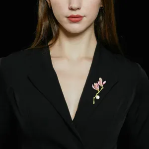 Close-up detail of the elegant magnolia flower brooch with pink enamel petals and pearl pendant.