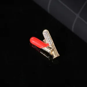 Detailed close-up of a creative medical syringe shaped brooch with rhinestones and red enamel.