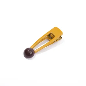 Dettaglio molletta per capelli in metallo giallo con perla sferica marrone, accessorio carino.
