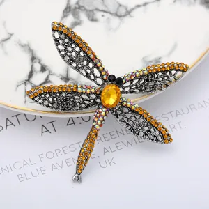 Exquisite dragonfly brooch with sparkling yellow rhinestones and hollow metallic wings design.