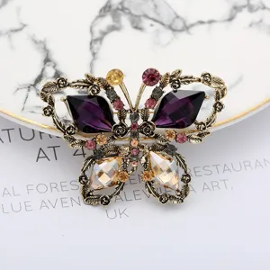 Close-up detail of vintage butterfly brooch with purple and champagne crystals on metal wings.