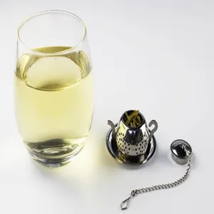 Stainless steel teapot shaped tea infuser and strainer detail view with clear glass cup.