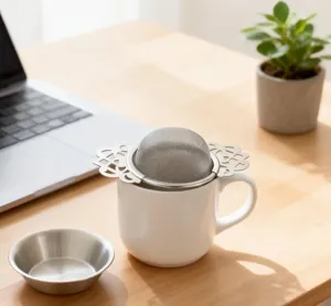 Edelstahl Tee-Sieb mit Spitzengriffen auf einer weißen Keramik Tasse für Ihren Lieblingstee.