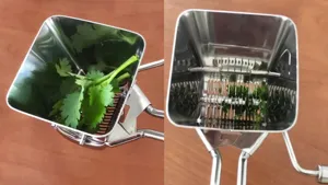Stainless steel manual herb cutter detail view showing clean rotating blades and chopped cilantro inside.