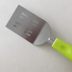 Stainless steel spatula detail shot, featuring slotted blade and bright green handle.