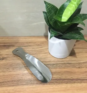 Close-up view of the portable stainless steel shoehorn detail on wooden desk, practical tool.