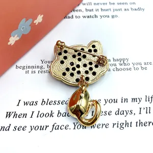 Cute cat brooch with sparkling rhinestones and dangling charm, elegant metal pin for apparel.