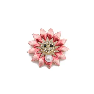 Spilla girasole rosa in smalto con viso sorridente in strass e ciondolo di perla per cappotto.
