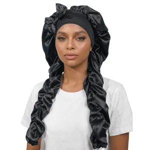 Detail view of the black satin sleep bonnet featuring long braided extensions and a bow.