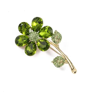 Green crystal flower brooch detail, elegant rhinestone plant pin accessory for women outfits.