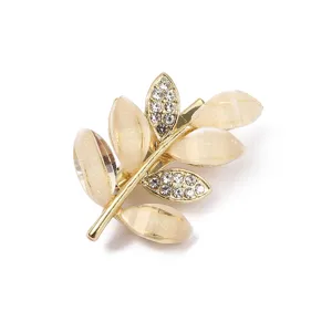 Nahaufnahme der eleganten Goldblatt-Brosche, verziert mit schimmernden Katzenaugen und Strasssteinen.