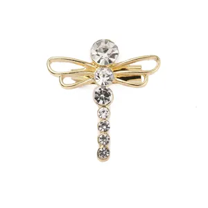 Detailaufnahme einer glitzernden Strass-Libellen-Brosche und Haarspange in Gold. Elegant.