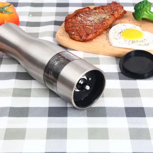 Stainless steel pepper grinder detail showing transparent spice chamber and ceramic grinding core.