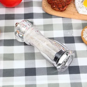 Detail view of transparent acrylic manual pepper grinder filled with salt and spices.