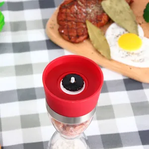 Moulin à sel et poivre manuel avec mécanisme en céramique, corps en verre et couvercle rouge.