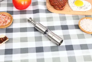 Stainless steel manual pepper grinder detail view, kitchen condiment mill tool close up view.